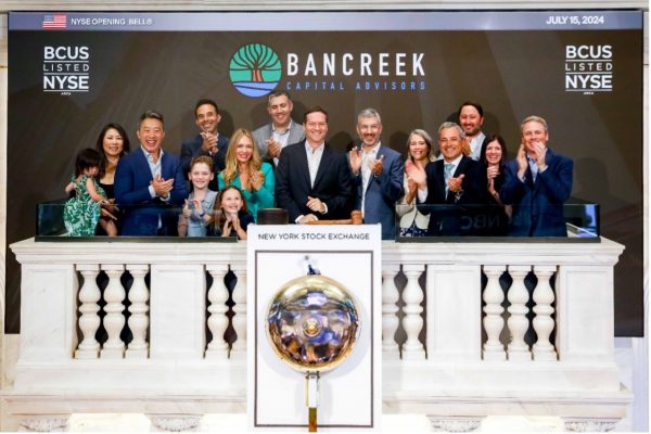 A group of about 20 people clap while ringing the NYSE bell.