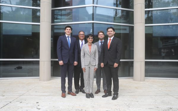 A group of four students and Eddie Sanchez pose together for a photo.