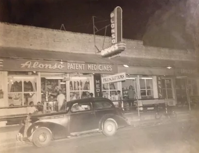 An old photograph of an outdated building and automobile.