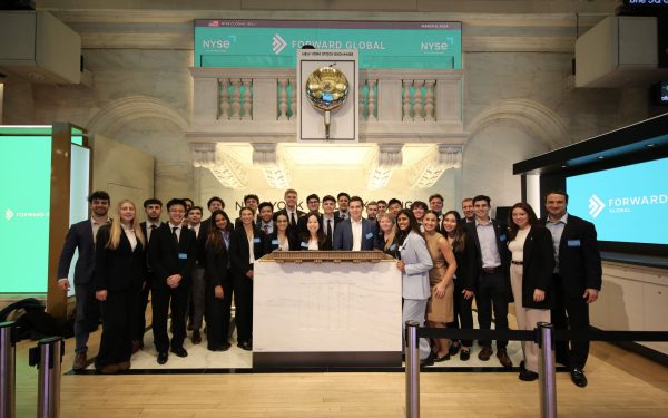 A large group of students stands at the opening bell of the New York Stock Exchange.