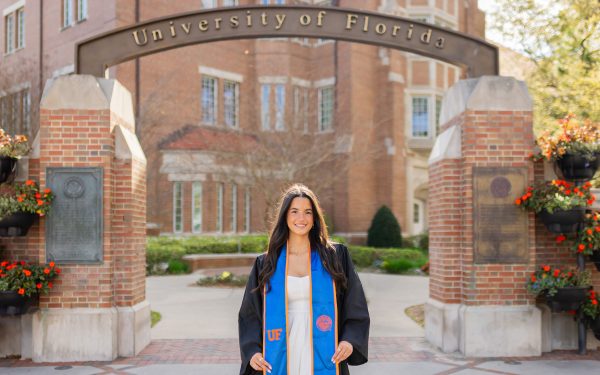 Nicole Acosta in graduate regalia under a University of Florida archway.