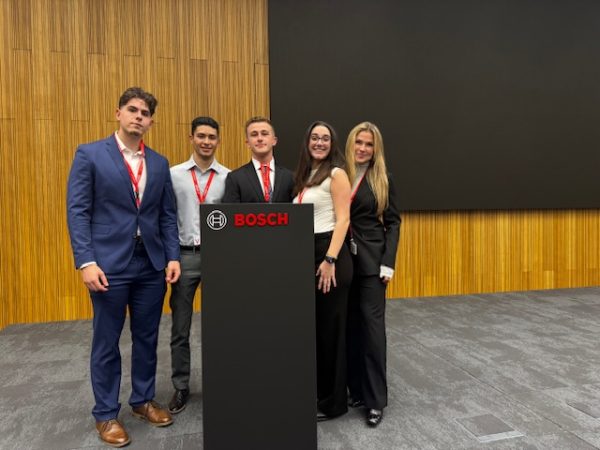 Mia Molinelli stands at a Bosch lectern with her team.