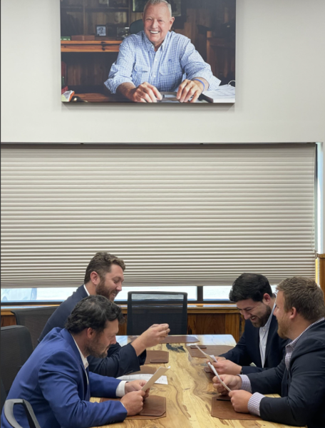 Bryan Doyle working with his colleagues under a portrait.