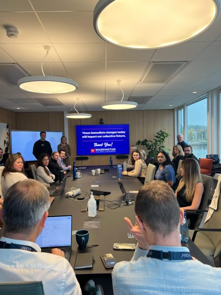 MBA students present a consulting project in a boardroom full of people.