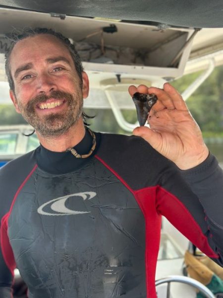 Trevor Foulk holds a shark tooth.