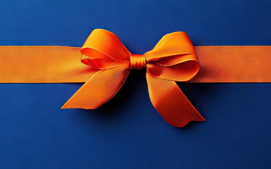 professional photo of orange ribbon and bow on royal blue background, gift wrap concept