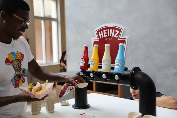 A student collects Heinz condiments with one hand while balancing food in the other.