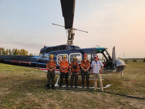 McHenry Priestly and four of his employees stand next to a helicopter.