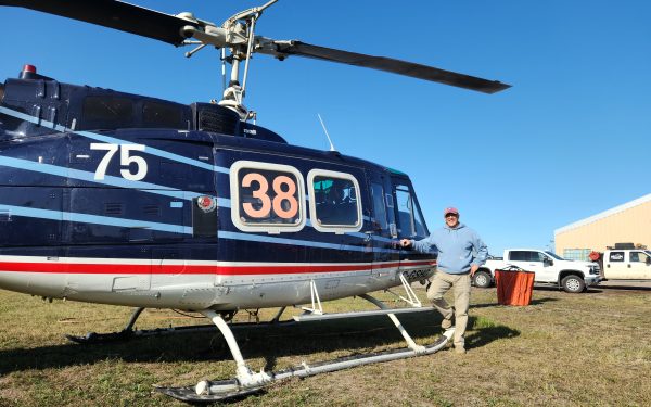 McHenry Priestly stands next to a helicopter