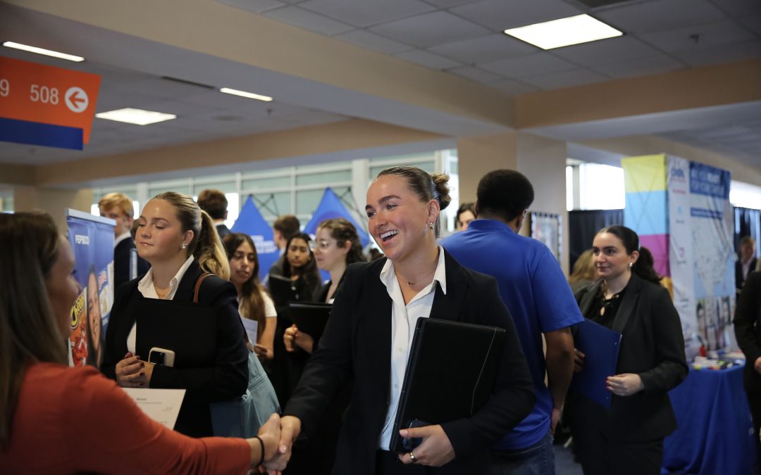 A female student shakes hands with a recruiter at a career fair.