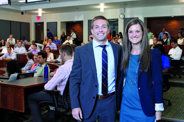 Michael and Sarah Peerson pose for a photo in a classroom full of students behind them.