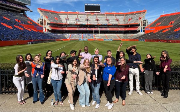 A group of about 20 students do the Gator chomp in Ben Hill Griffin Stadium.