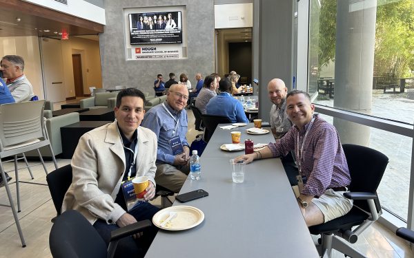Four men sit at a table while eating lunch during DBA Alumni Weekend.