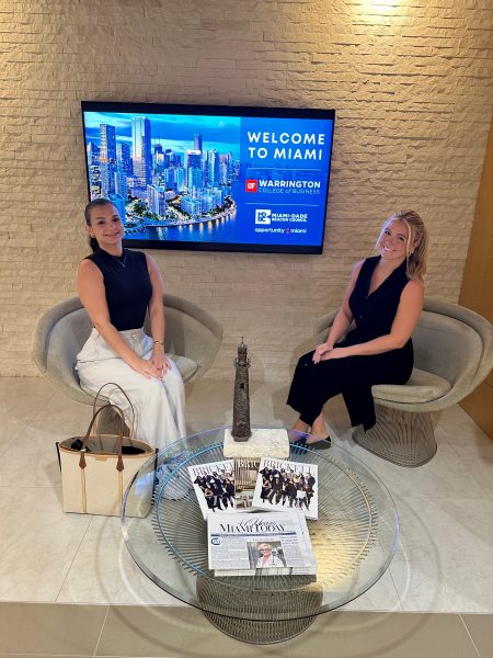 Ariella Ciuraru (BSBA ’23, MSMAR ’24) at the Miami Marketing Consulting Immersion Experience posing for a photo sitting down in front of a TV with another person.
