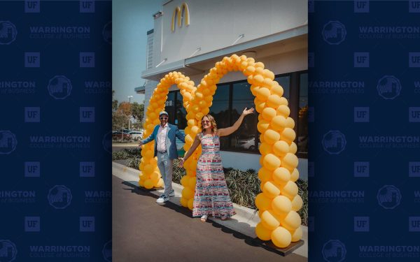 David Costa and his wife pose in front of a McDonald's M balloon arch at the opening of one of their store locations.