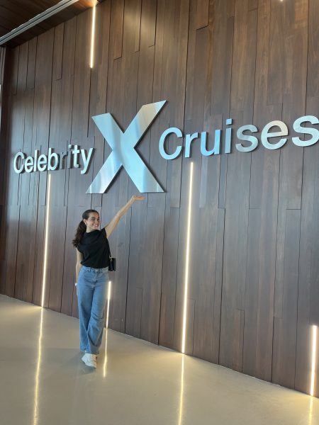 emily granda posing with a hand up in front of a celebrity cruise sign