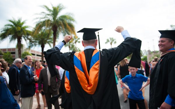 back of uf graduate with cap and gown with his hands up