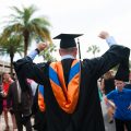 back of uf graduate with cap and gown with his hands up