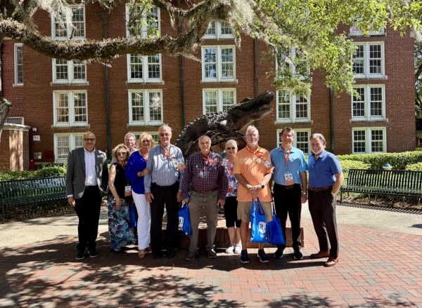 A group of about 10 alumni pose for a photo during a 50 year class reunion.