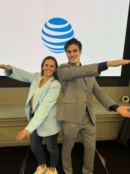 UF alumna Danielle Houghton and Warrington student Ethan Belforte doing the gator chomp in front of the AT&T logo